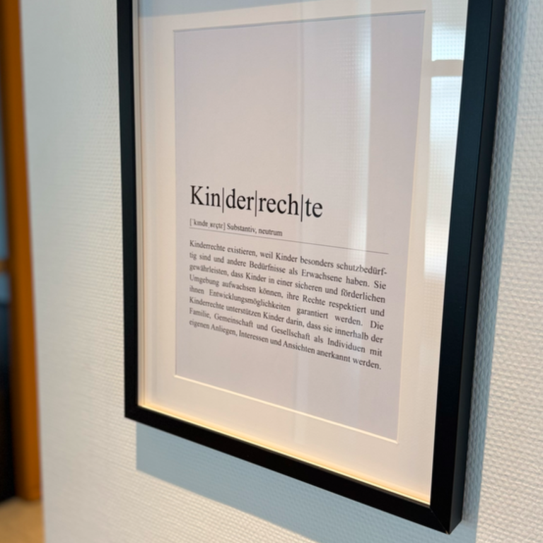 Gerahmter Text über das Thema Kinderdemokratie an einer Wand.