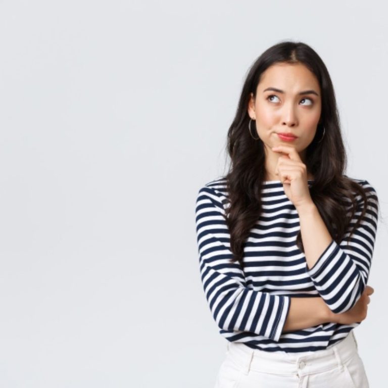 Junge Frau mit nachdenklichem Blick in gestreiftem Shirt und weißen Hosen.